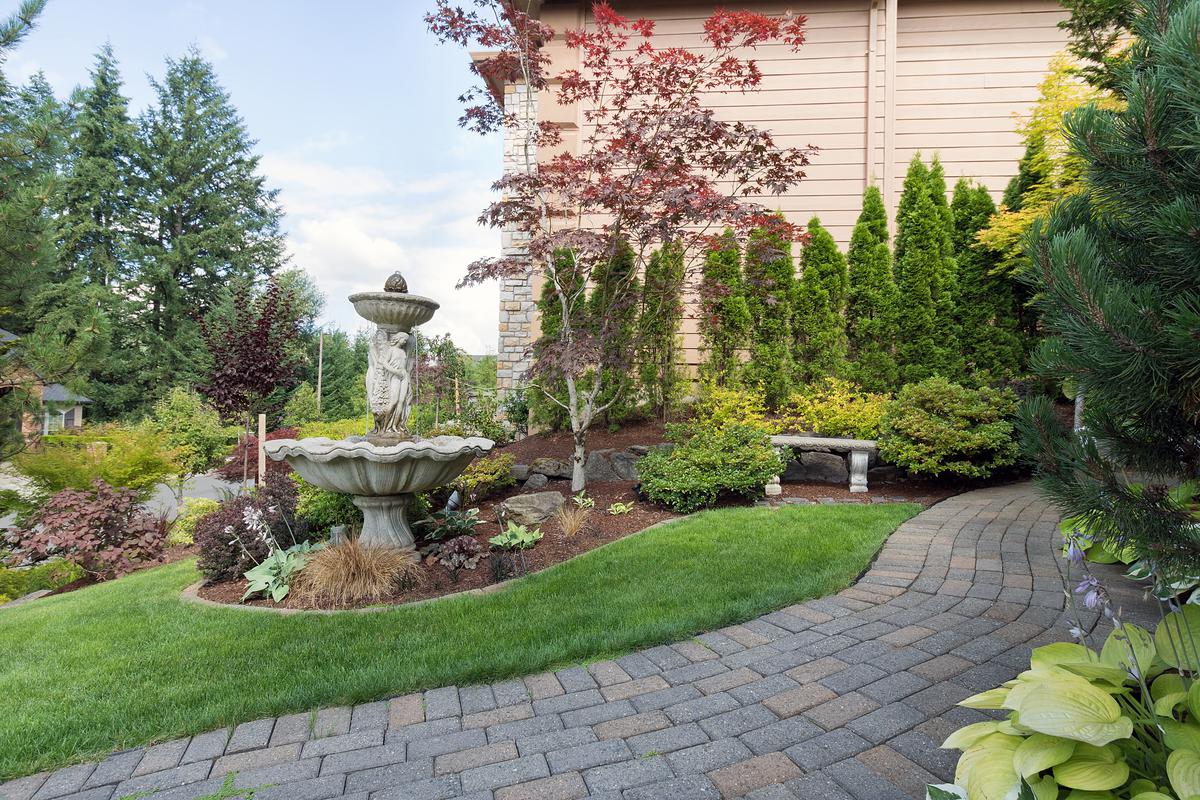 A mesmerizing water feature gracefully nestled in the front yard creates a serene sanctuary, where the soothing sounds of flowing water invite peace and tranquility.